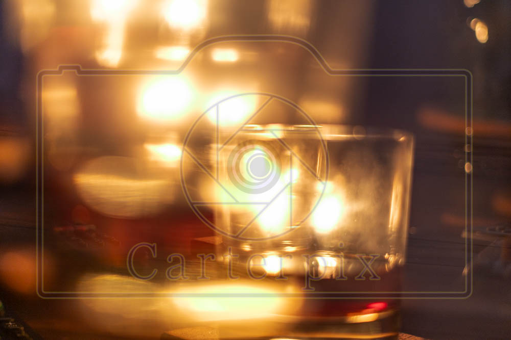 Water marked / artsy burning candle behind a glass.