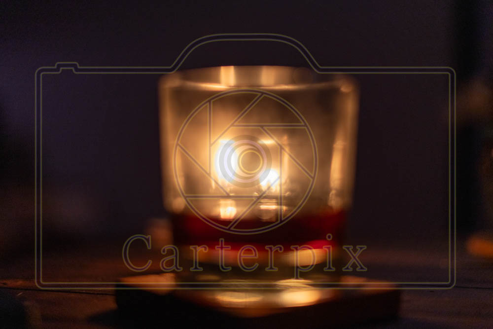 Water marked / artsy burning candle behind a glass.