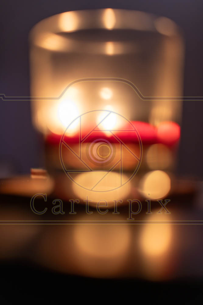 Water marked / artsy burning candle behind a glass.