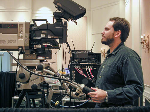 Craig running a video camera with telephoto lens at a conference many many years ago